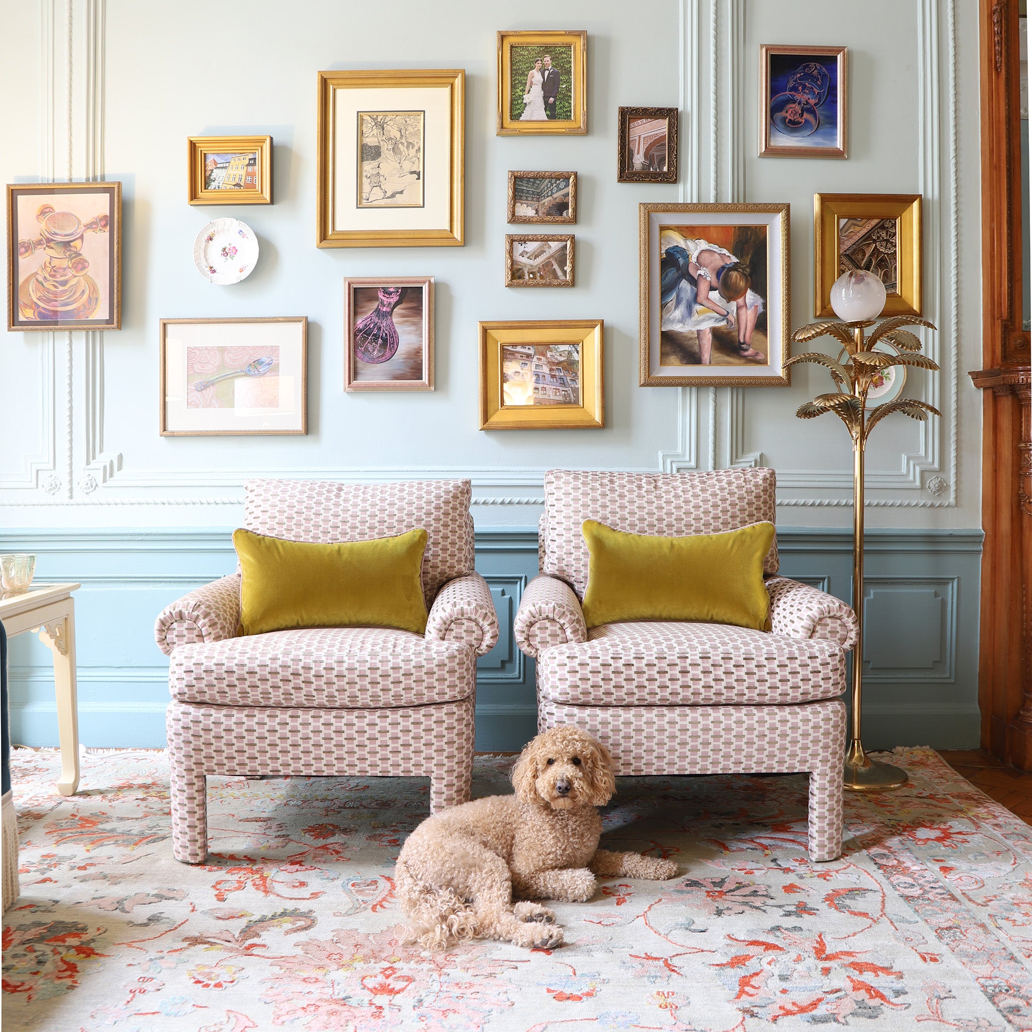 chenille and woven jacquard pink and citron geometric chairs with golden chartreuse pillows on them in front of a blue wall with artwork hung on the wall
