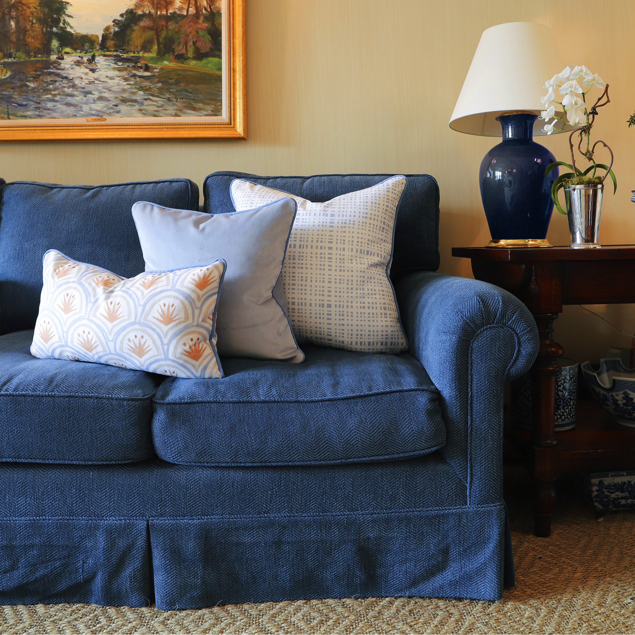 Ginger fabric pillows with blue grid and floral patterns on classic blue couch, made-to-order in the USA with quick turnaround